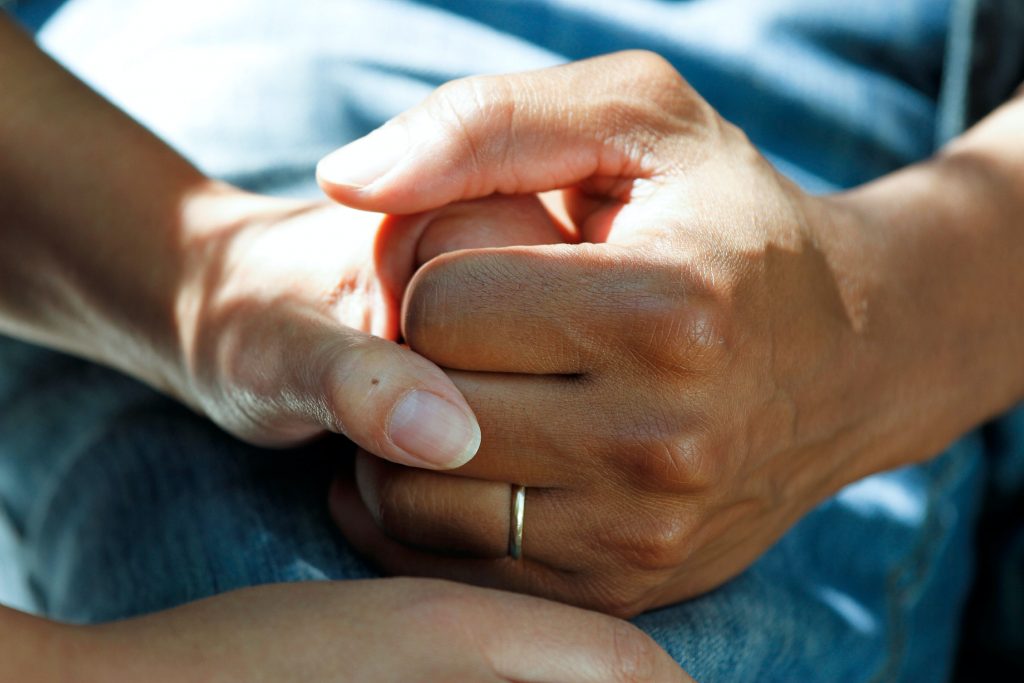 Two people holding hands on a blue bed